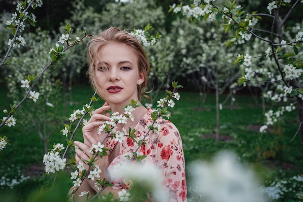 Belle jeune femme dans le jardin de cerisiers en fleurs.