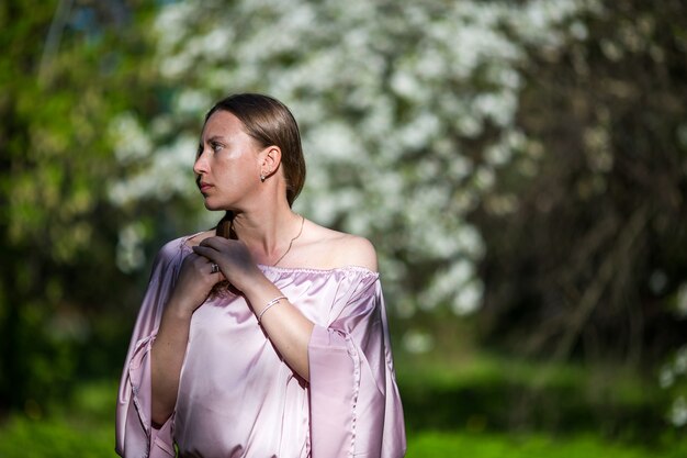 Belle jeune femme dans le jardin des cerisiers en fleurs