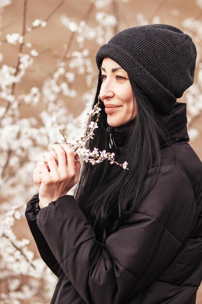 Belle jeune femme dans un jardin de fleurs de cerisier en fleurs