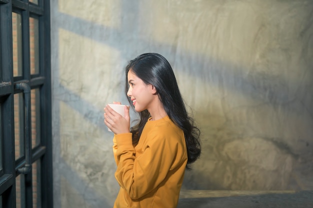 Une belle jeune femme dans la lumière du soleil appréciant son café du matin à la maison