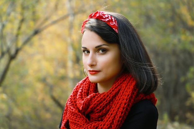 Belle jeune femme dans un manteau blanc au crochet Écharpe rouge et chapeau noir Portrait en plein air d'automne