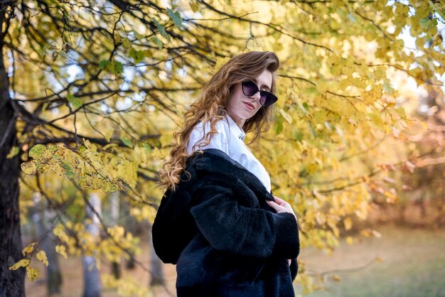 Belle jeune femme dans un manteau de fourrure dans la forêt d'automne magique.