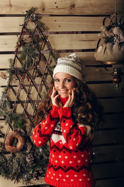 Belle jeune femme dans un mode d'hiver tourné portant un bonnet blanc en laine, un pull en laine rouge