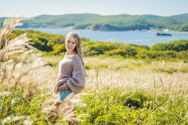 Belle jeune femme dans un paysage d'automne avec des fleurs sèches, des épis de blé. Mode automne, hiver. Automne ensoleillé, pull d'automne confortable. photos de mode