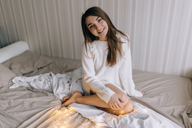 Belle jeune femme dans un pull chaud dans une chambre lumineuse le matin.