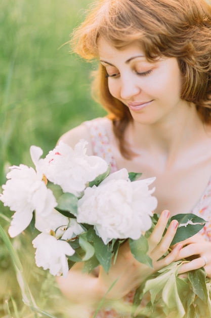 Belle jeune femme dans une robe d'été avec des pivoines