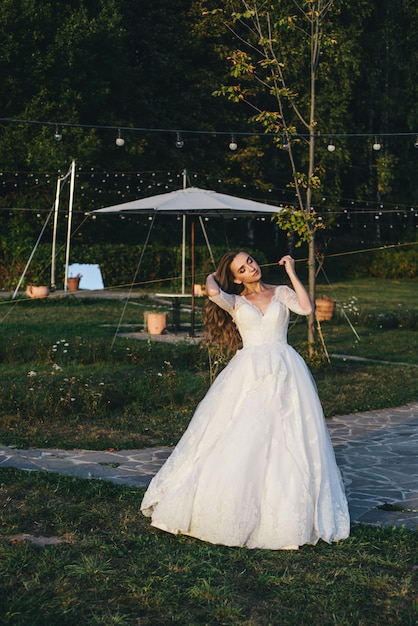 Belle jeune femme dans une robe de mariée blanche et des bottes noires au coucher du soleil.