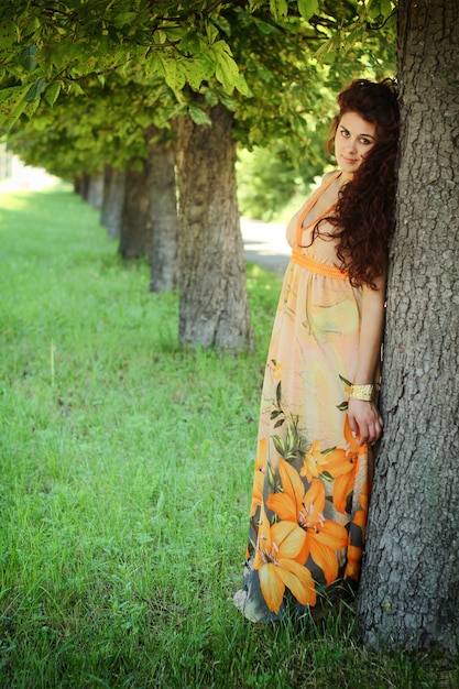 Belle jeune femme dans une robe près de l'arbre