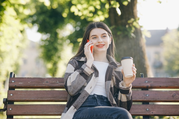 Belle jeune femme debout sur un banc à l'aide du téléphone