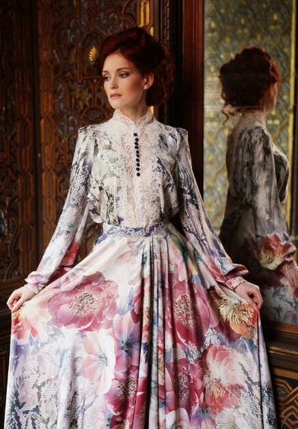 Belle jeune femme debout dans la salle du palais avec miroir.