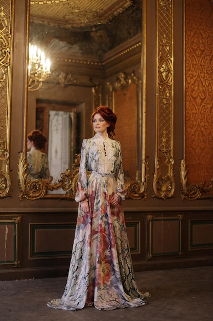 Belle jeune femme debout dans la salle du palais avec miroir