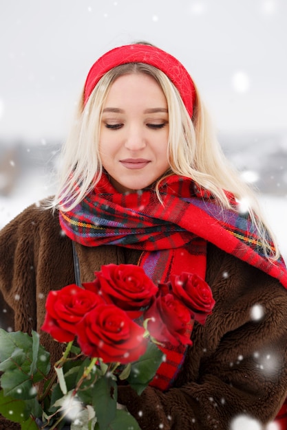 Belle jeune femme donne un bouquet de roses rouges le jour de la Saint-Valentin