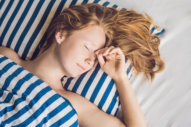 Belle jeune femme dormant dans son lit et se relaxant le matin