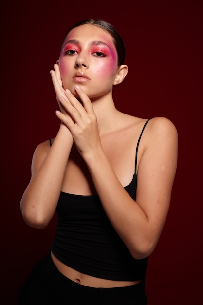 Belle jeune femme avec du maquillage créatif sur son visage posant sur fond en studio