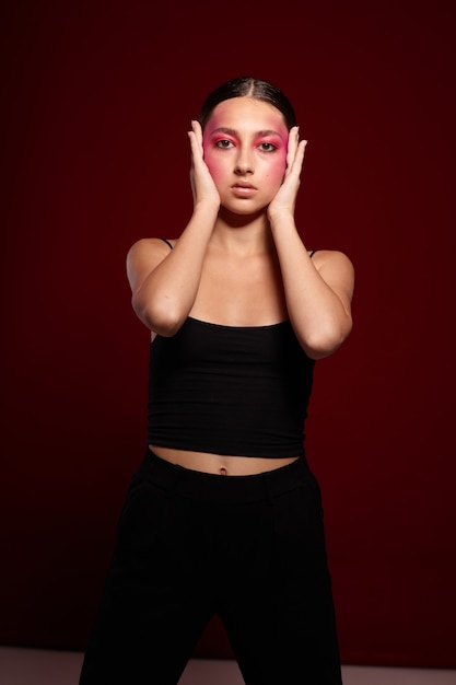 Belle jeune femme avec du maquillage créatif sur son visage posant sur fond en studio