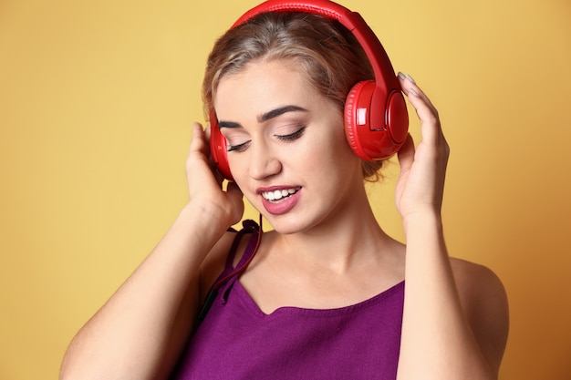 Belle jeune femme écoutant de la musique sur fond de couleur