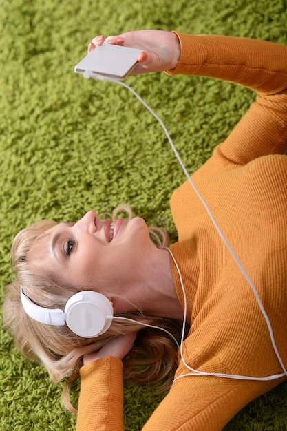 Belle jeune femme écoutant de la musique à la maison sur le sol