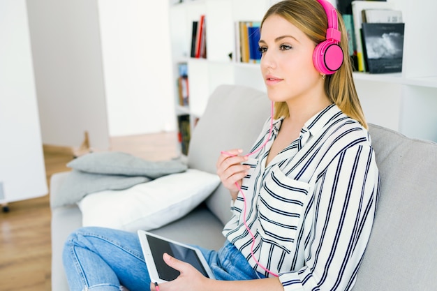 Belle jeune femme écoutant de la musique avec une tablette numérique.