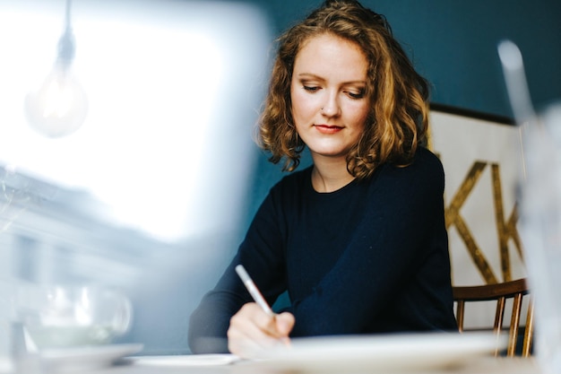 Photo une belle jeune femme écrit sur la table au café.