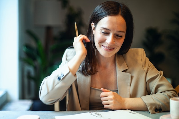 Belle jeune femme écrivant ses plans d'affaires sur le journal