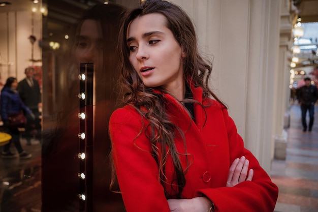 Belle jeune femme élégante dans un long manteau bordeaux boutique intérieure grand magasin dans les décorations de Noël Moscou