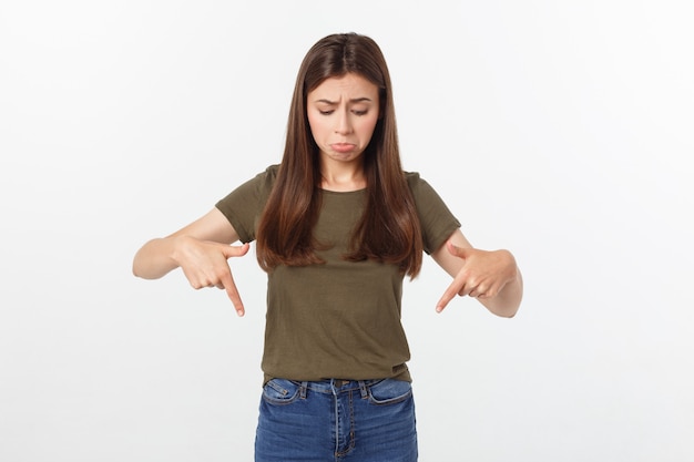 Belle jeune femme élégante sur fond isolé, pointant la main et les doigts avec une expression triste.