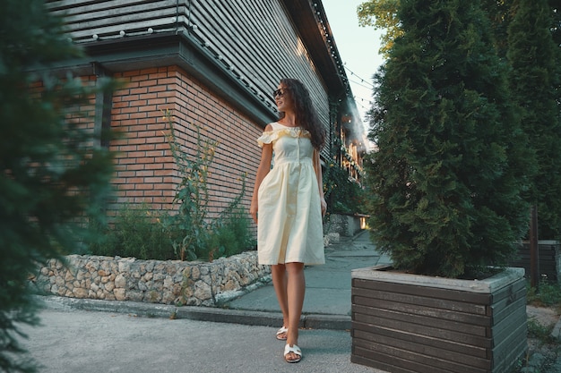 Belle jeune femme élégante à lunettes de soleil marchant sur une robe d'été