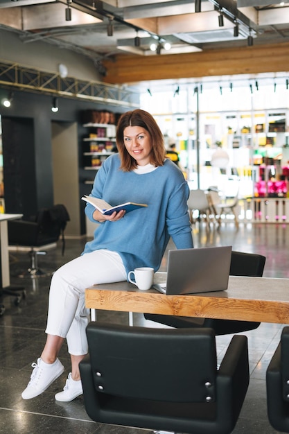 Belle jeune femme élégante, plus le corps de taille positive à l'aide d'un ordinateur portable au propriétaire du bureau du salon de beauté