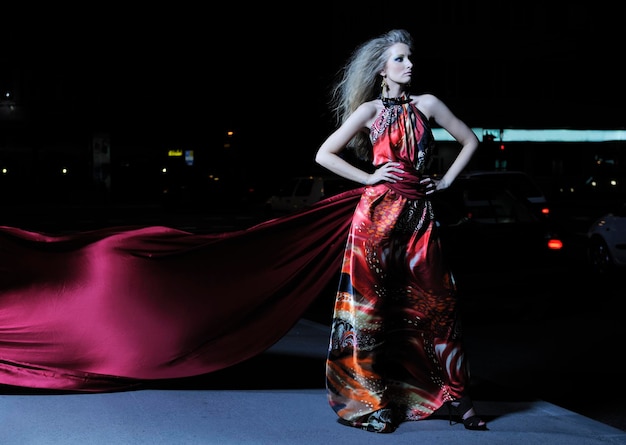 Photo une belle jeune femme élégante en robe de mode et de style urbain en ville dans la rue la nuit seule