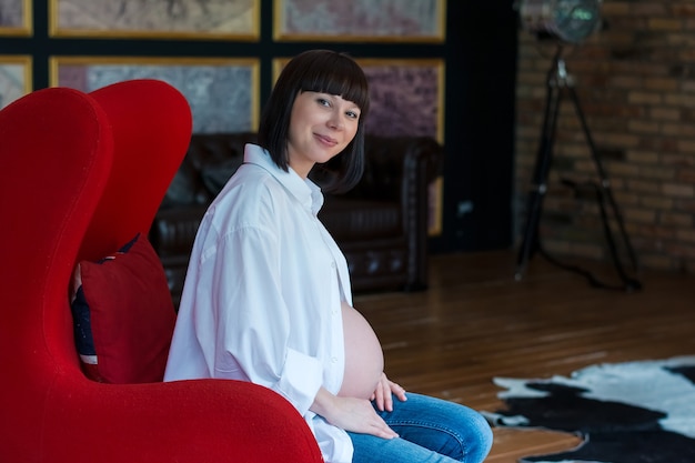 Belle jeune femme enceinte assise sur une chaise