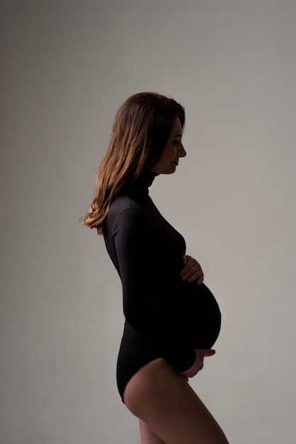 Belle jeune femme enceinte en body noir.