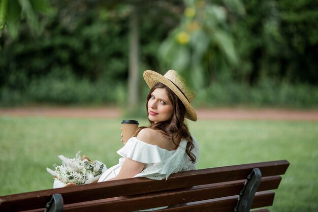 Belle jeune femme enceinte boit du cappuccino dans le parc