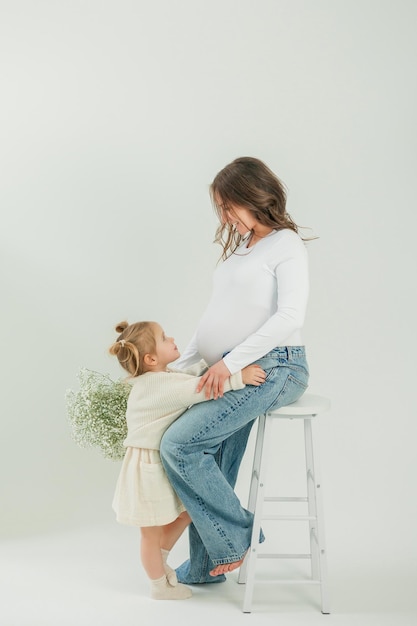 Photo une belle jeune femme enceinte avec un bouquet de fleurs de printemps avec sa petite fille de 3 ans