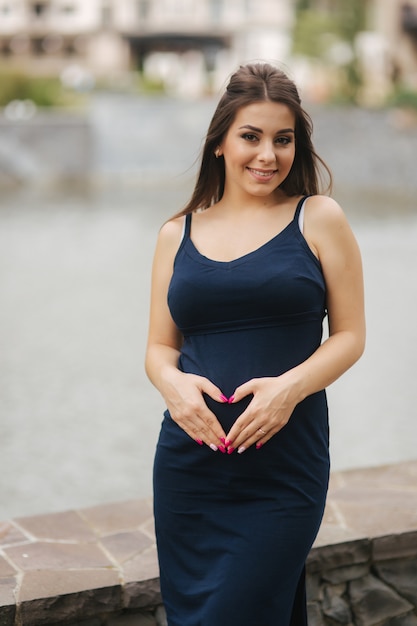 Belle jeune femme enceinte debout près du lac.