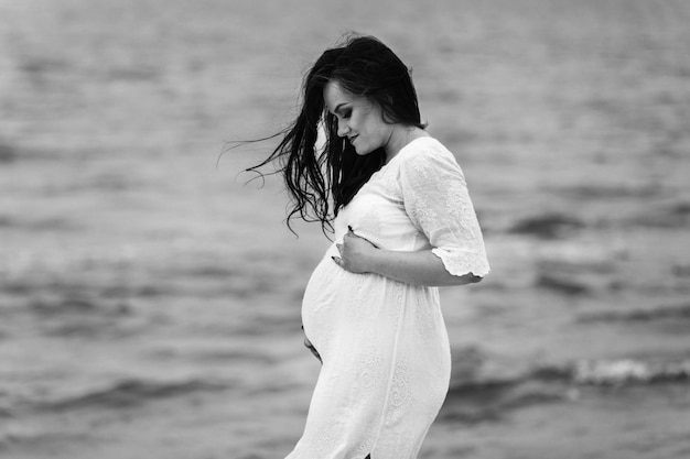 Belle jeune femme enceinte marchant sur la plage