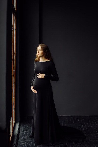 Belle jeune femme enceinte en robe noire Concept de look de mode de grossesse