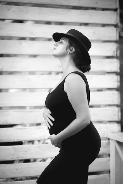 Photo belle jeune femme enceinte en robe noire posant à l'extérieur place pour texte italie
