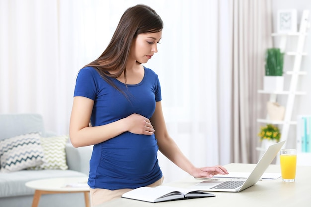 Belle jeune femme enceinte travaillant à la maison