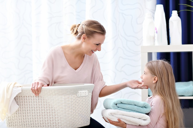 belle jeune femme et enfant fille s'amusant tout en faisant la lessive à la maison