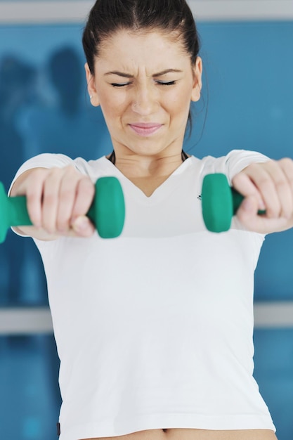 Belle jeune femme d'entraînement de fitness avec des poids au club de sport