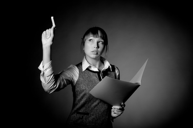 Belle jeune femme avec une enveloppe pour papiers écrit à la craie sur un tableau de craie invisible