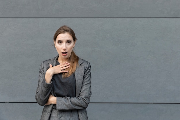 Belle jeune femme est debout dans un costume gris. La femme d'affaires est très surprise, face à son malentendu de ce qui se passe.