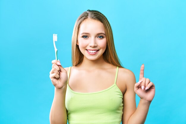 Belle jeune femme est engagée dans le nettoyage des dents. Beau sourire dents blanches saines. Une fille tient une brosse à dents. Le concept d'hygiène buccale. Image promotionnelle pour une stomatologie, clinique dentaire