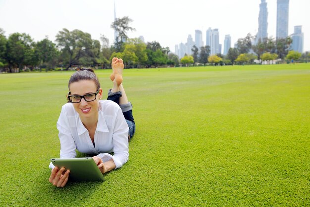 Belle jeune femme étudiante étudie avec tablette dans le parc