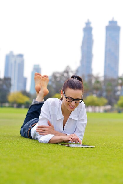 Belle jeune femme étudiante étudie avec tablette dans le parc