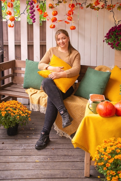 belle jeune femme à l'extérieur en automne près de la maison sur le porche