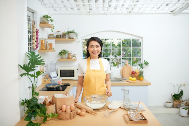 Belle jeune femme faisant cuire la pâtisserie dans la cuisine