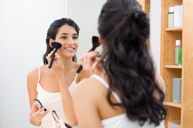 Belle jeune femme faisant du maquillage dans sa salle de bain