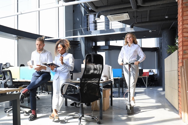 Belle jeune femme faisant du scooter au bureau moderne de l'espace ouvert.