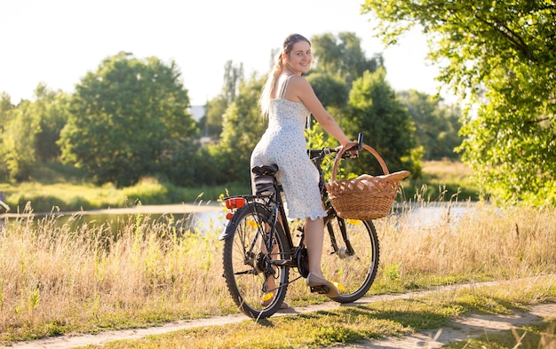 Belle Jeune Femme Faisant Du Vélo Au Bord De La Rivière à Une Chaude Journée Ensoleillée